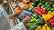© Oulaphone - A person using a tablet to manage or inspect fresh produce in a grocery store filled with colorful fruits and vegetables.