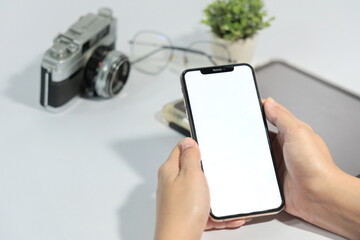 A person is holding a phone with a camera on the table