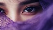 © familymedia - A compelling close-up image focuses on deep brown eyes partly obscured by a purple veil, creating an aura of mystery and allure through rich colors and textures.