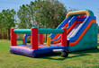 © Lorena - A colorful inflatable slide features for kids on the green grass with trees on background