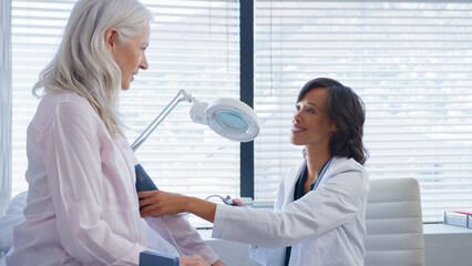 Poster - Mature Woman Patient Having Blood Pressure Taken By Female Doctor In Office