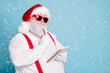 © deagreez - Close up photo of focused funny funky fat santa claus hold notebook think about wish list plan decide what choose look thoughtful wear stylish trendy suspenders isolated over blue color background