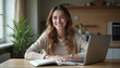 © dapra01 - An attractive woman sitting at her desk, using a laptop and a notebook, studying online at home with a smile