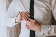 © Vasil - A man is getting ready to tie his tie. He is wearing a white shirt and a black tie