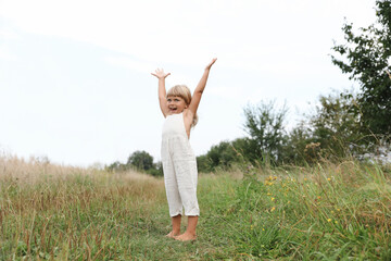 Canvas Print - Cute little girl walking barefoot at meadow. Child enjoying beautiful nature