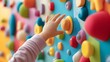 © thanarak - Close up of a young child s hand reaching out to explore the colorful and textured sensory wall