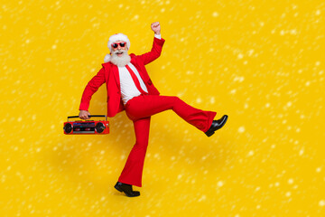 Wall Mural - Full length photo of funky cool santa dressed red suit tie enjoying boom box songs walking empty space isolated yellow color background