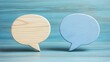 © Papugrat - Two wooden speech bubbles, one natural wood and one blue, resting on a wooden background The image represents communication, dialogue, or discussion in a simple and modern way