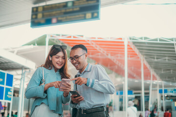 Two cheerful travelers excitedly enjoying their trip planning while at the busy airport