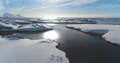 Antarctica ocean bay coastline winter landscape. Snow-covered rocky land under bright sun blue sky. Untouched wilderness of Antarctic nature, mountains in background. Explore travel to South Pole