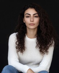 A beautiful young woman with curly hair wearing a white sweater