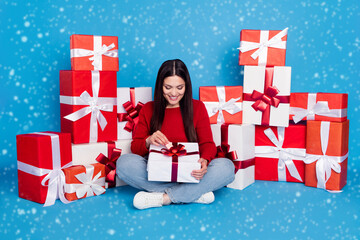 Sticker - Portrait of lovely cheerful woman sitting opening festal giftboxes eve isolated over bright blue color background