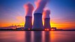 © BerkahStock - Three cooling towers with steam against a colorful sunset.
