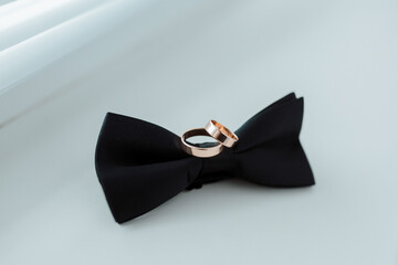 Wall Mural - Two rings are on a black bow tie. The rings are gold and are placed on top of each other