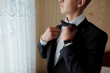 Wall Mural - A man in a suit is getting ready to tie his bow tie. Concept of formality and elegance, as the man is dressed in a suit and tie