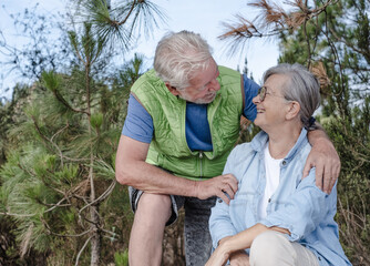 Senior couple sitting in the woods looking at each other with affection. Smiling elderly man and woman enjoying the freedom of the outdoors and healthy lifestyle in retirement