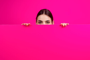 Beautiful woman showing a board. Woman pointing at the board. Woman holding blank card. Promo advertising. Presenting something on white blank board with empty space. Presents blank board.