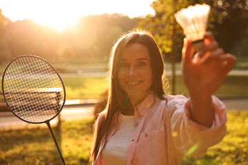 Poster - Happy young woman with badminton racket and shuttlecock in park on sunny day, selective focus