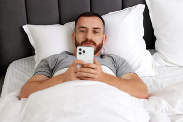 Poster - Handsome man using mobile phone in bed