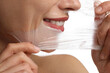 © New Africa - Smiling woman peeling off face mask on white background, closeup