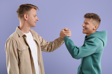 Poster - Happy brothers clasping hands on violet background