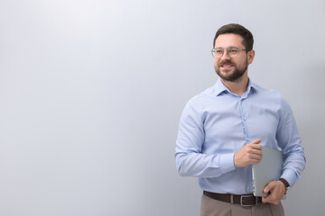 Wall Mural - Portrait of smiling businessman with laptop on grey background. Space for text