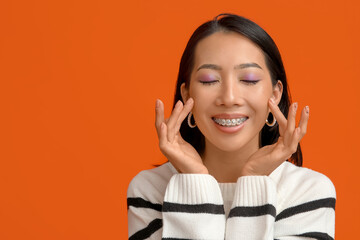 Wall Mural - Young Asian woman with beautiful makeup on orange background