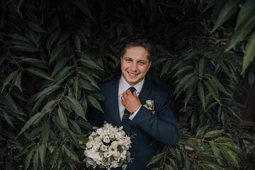 Wall Mural - A man in a suit and tie is posing with a bouquet of flowers. He is smiling and he is happy