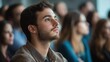 © Daniel - man sitting in a crowd of people listening to a presentation, selective focus, business photography