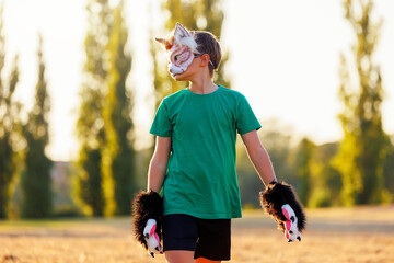 Confident young little kid boy wear cat furry mask enjoy have fun playing outdoors in forest street park. Children therian wild animal character trendy fan culture. Teenager social expression hobby