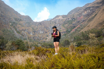 Wall Mural - Atractiva joven turista con short  responde a videollamadas al aire libre, chica inteligente se comunica con entusiasmo en conferencia en línea al aire libre,  turista hablando de grabar contenido