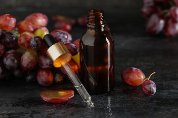 Wall Mural - Bottle of cosmetic grape seed oil on black background