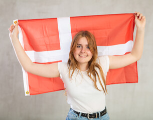 Pretty young female sudent holding the Danish flag in her hands