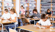 © JackF - Teenage boys and girls reading books and doing homework in library.