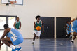 © Wavebreak Media - Playing basketball, man dribbling ball on indoor court with teammates