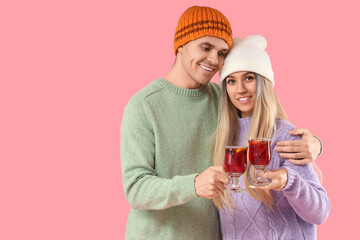 Wall Mural - Happy young couple with mulled wine on pink background