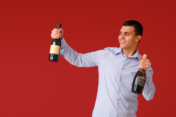 Poster - Young man with bottles of champagne celebrating Christmas on red background