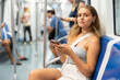 © JackF - Pensive young woman passenger using smartphone sitting in underground train
