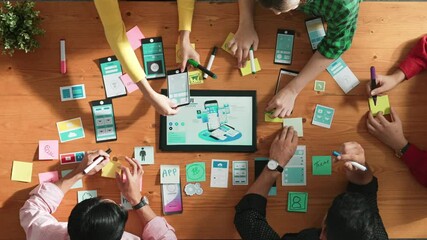 Programmer sharing Ux Ui design for mobile phone interface idea with software developer while designer writing idea at sticky notes. Start up team develop wireframe prototype. Time lapse. Convocation.