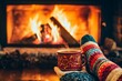 © adri - Warm mug of hot drink with steam, held by a hand in a cozy knitted sock, in front of a fireplace with glowing embers.