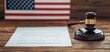 © Naphol - Gavel and document on wooden table with American flag in background, legal concept.