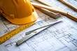 © adri - Close up of a construction plan with a yellow hard hat, ruler, and metal ruler.