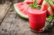 © Luxetify - A glass of refreshing watermelon smoothie with mint leaves on top, next to slices of watermelon on a rustic wooden table.