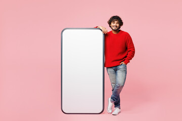 Poster - Full body young fun Indian man he wear red sweater casual clothes big huge blank screen mobile cell phone smartphone with area look camera isolated on plain pink background studio. Lifestyle concept.