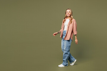 Wall Mural - Full body side view young happy cheerful cool woman she wears red shirt white t-shirt casual clothes walk go look camera isolated on plain pastel green background studio portrait. Lifestyle concept.