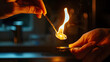 © Lotti - A person heating a spoon with a flame for cooking or stirring purposes in kitchen.