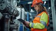 © Old Man Stocker - Female Worker in High Visibility Safety Gear. Female worker in high visibility safety gear uses a tablet while monitoring machinery in an industrial setting. Focused and professional.