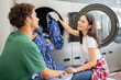 © Prostock-studio - A man and woman are interacting while doing laundry in a laundromat. The woman places clothes into the washing machine, smiling as she enjoys the shared task.