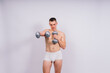 © Ivan Zelenin - Muscular young man in white underwear with dumbbell in studio background
