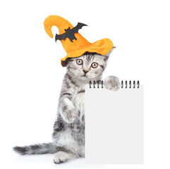 Poster - Cute Kitten with hat for halloween shows blank notepad. Empty space for text. isolated on white background
